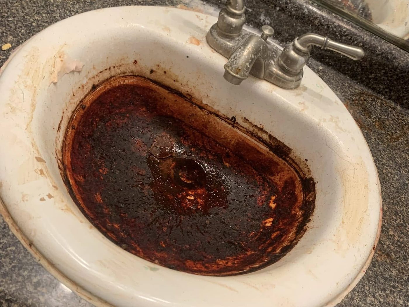 A rusted, stained bathroom sink before resurfacing