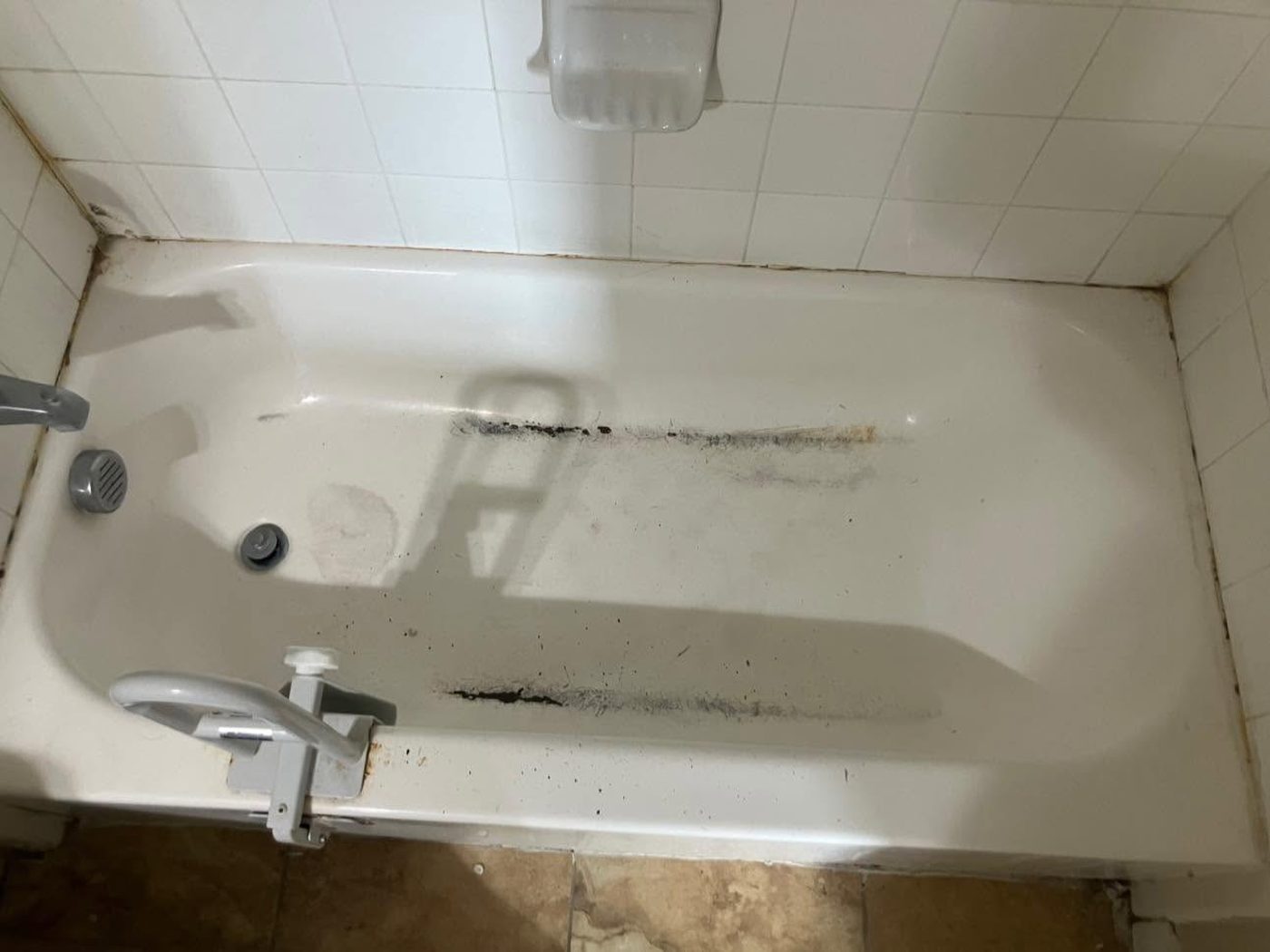 A stained, worn apartment bathtub before resurfacing