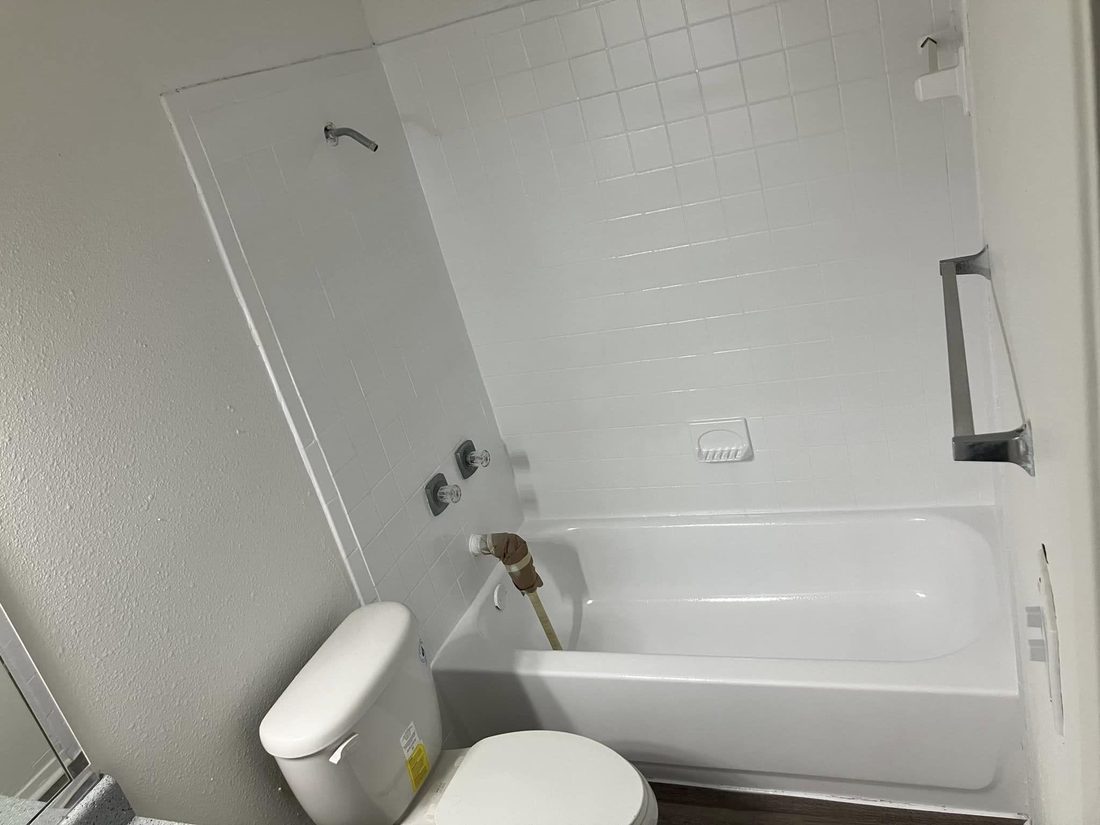 A resurfaced apartment bathroom, tub and surround bright white