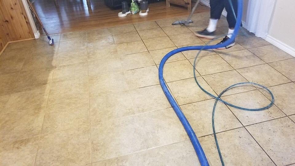 A tech running extraction hoses across a tile floor