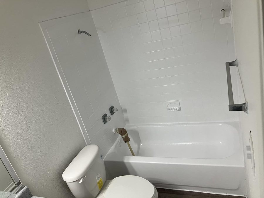 A resurfaced white tub and bathroom in an apartment unit