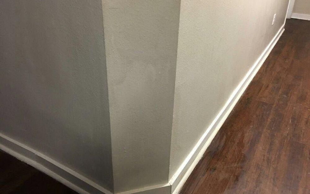 A repaired and painted wall corner with new baseboard